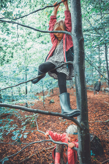Low angle view of woman hanging on rope in forest