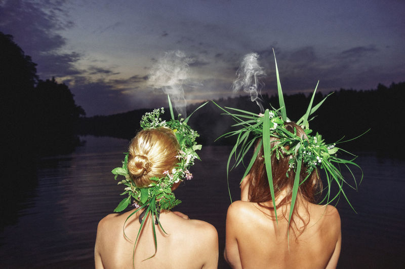 Rear view of women with plant against river