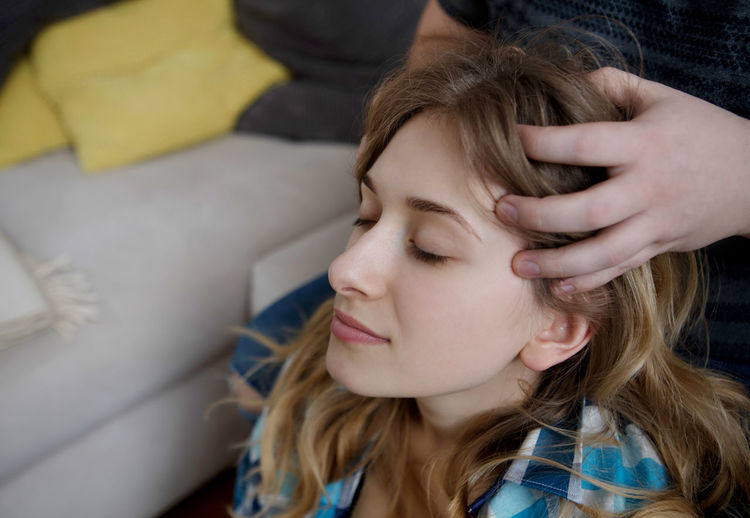 Midsection of boyfriend giving girlfriend head massage at home