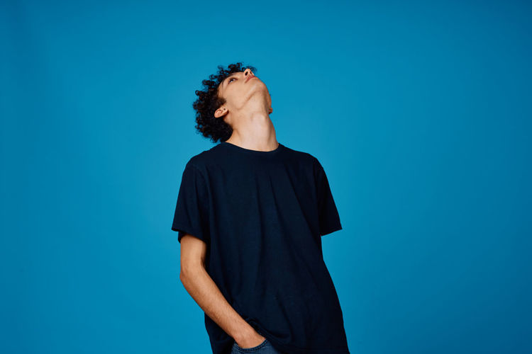 Rear view of man standing against blue background