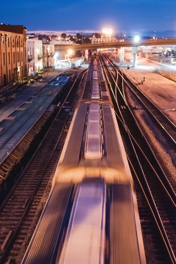 Railroad tracks against illuminated sky at night