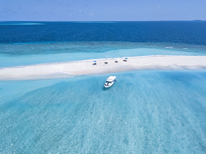 Maldives, aerial view of boat near small sandy islet off coast of indian ocean in summer