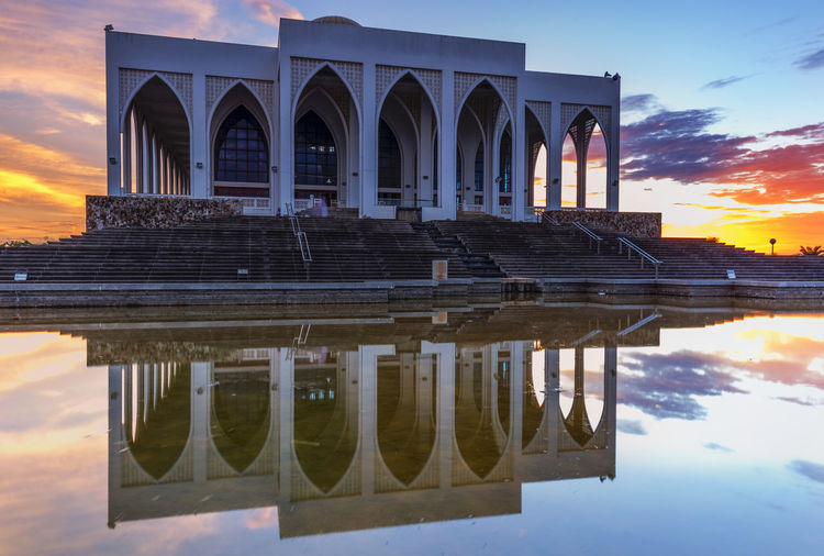 Historical building reflecting in pool during sunset