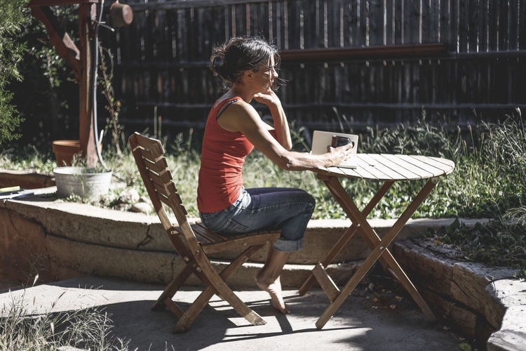Woman having coffee while sitting on chair at yard