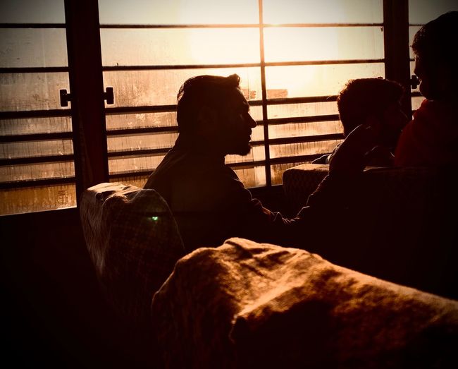 Rear view of people sitting on window