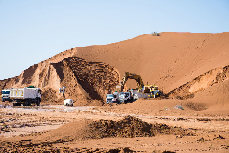 Bulldozer working at desert against sky