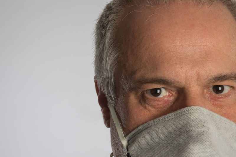 Close-up portrait of a man in face mask looking at camera. white background and copy space. 