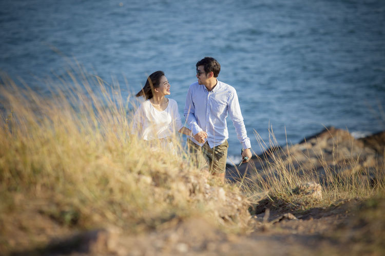 High angle view of couple walking on hill against sea