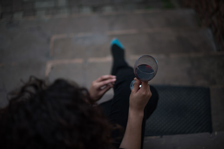 High angle view of woman holding red wineglass