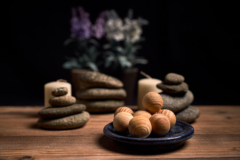 Composition of candles, stones and wooden spa balls on a wood and a black background