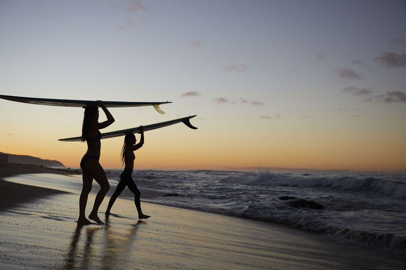 Girls paddling out for sunset surf on the north shore in hawaii