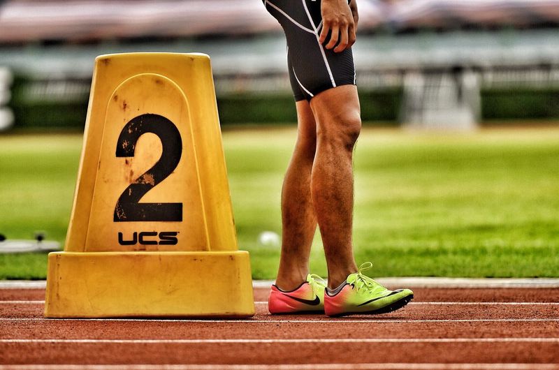 Low section of man standing on running track