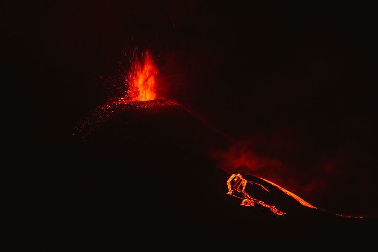 Breathtaking scenery of hot bright orange lava pouring out of erupting volcano against dark night sky in la palma island