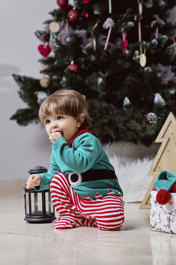 Boy sitting on christmas tree at home