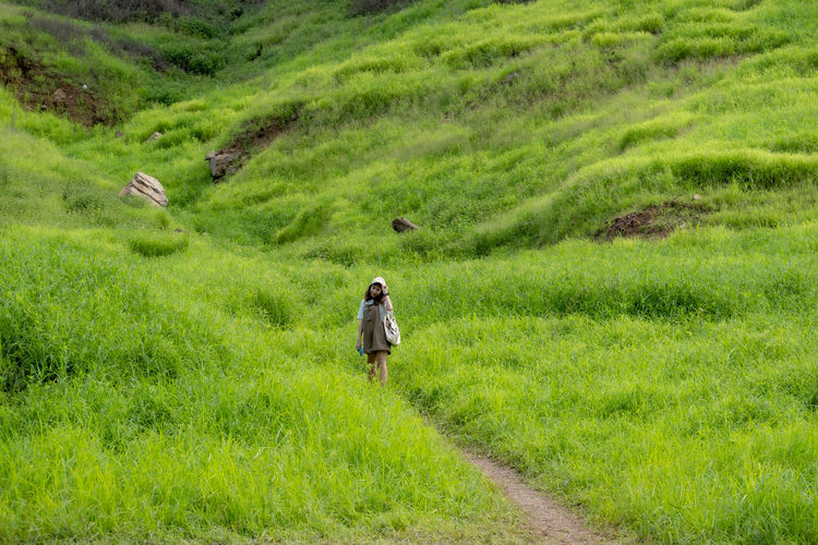 Rear view of woman walking on grassy field
