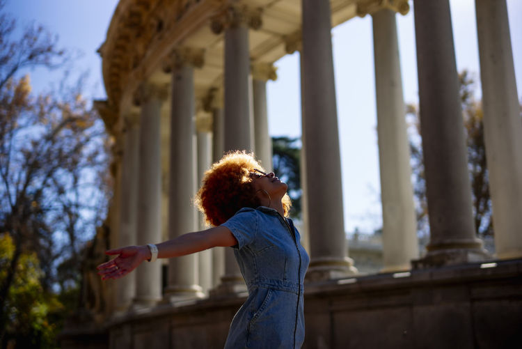 Mid adult woman with arms outstretched standing at parque del buen retiro, parque del buen retiro, spain