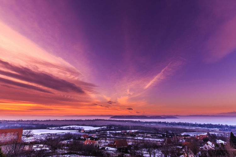 Low angle view of cloudy sky during sunset over snow covered landscape