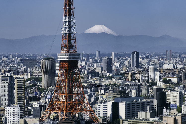 Tokyo tower amidst buildings against sky in city