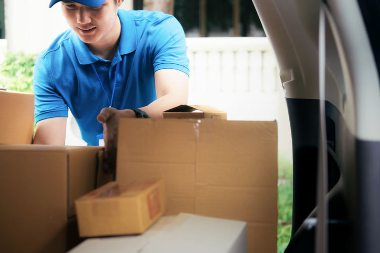 Delivery man removing packages from car