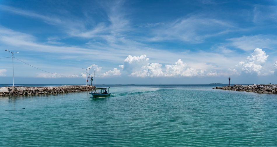 Motorboat sailing in sea against sky