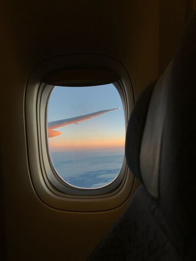 Airplane wing seen through window during sunset