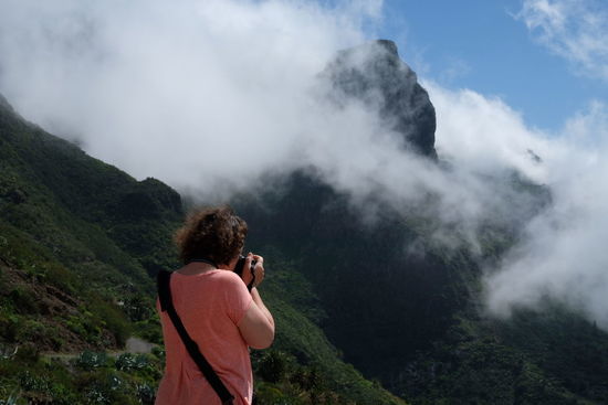 Rear view of woman photographing while standing on mountain
