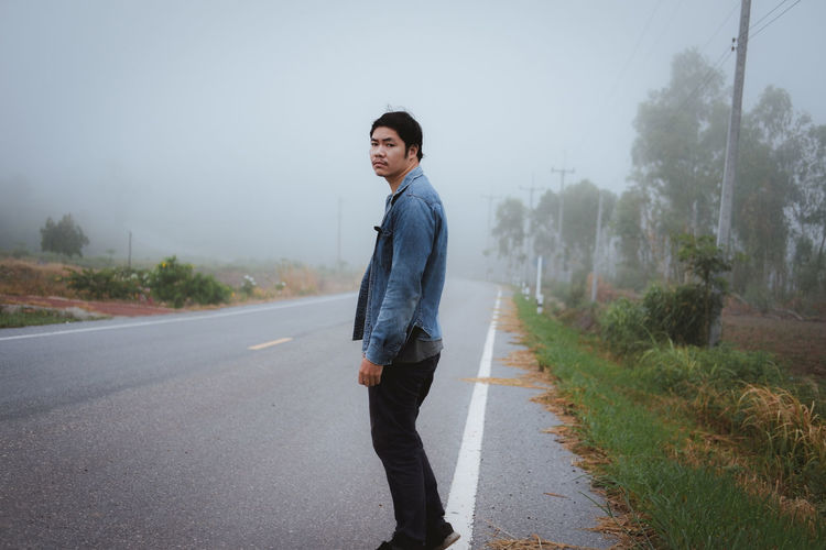 Full length portrait of young man standing on road