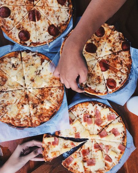 Cropped image of hands holding pizza on table
