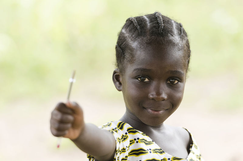 Portrait of girl holding pen outdoors