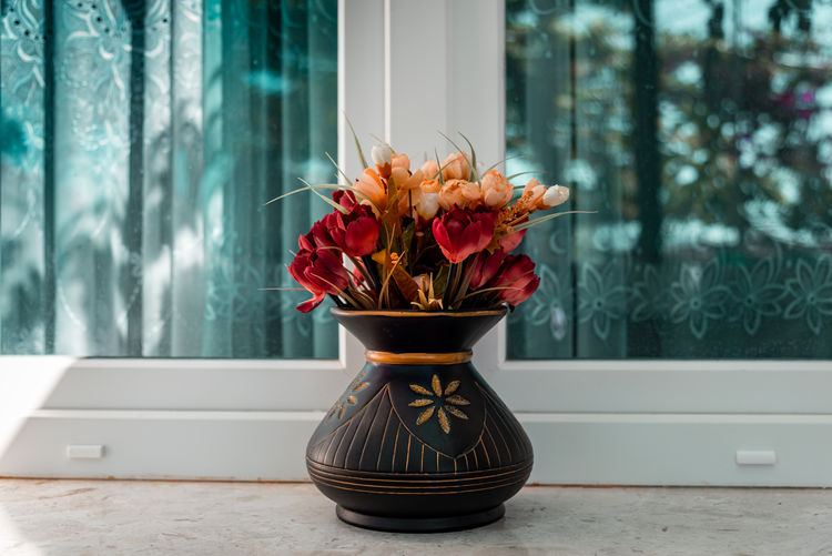 Flower vase on table against window
