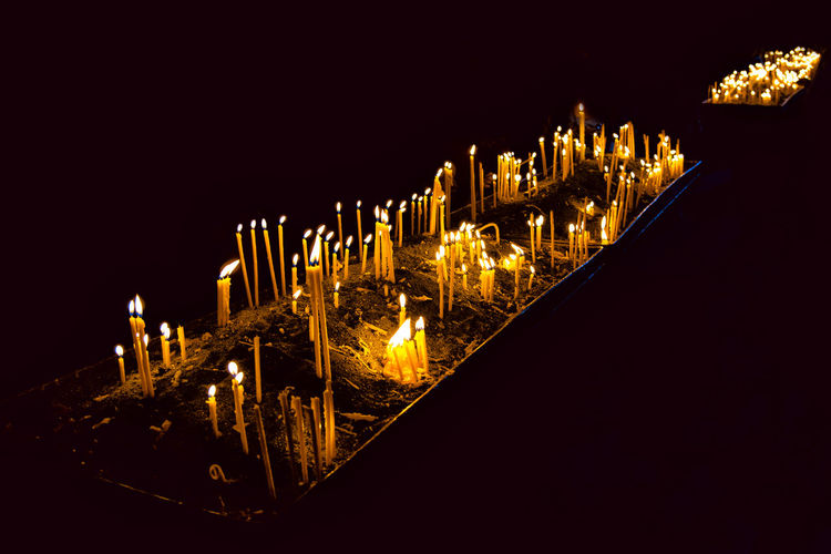 Close-up of illuminated candles against clear sky at night