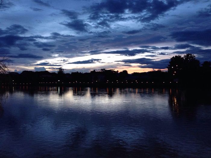 Scenic view of river against cloudy sky at dusk