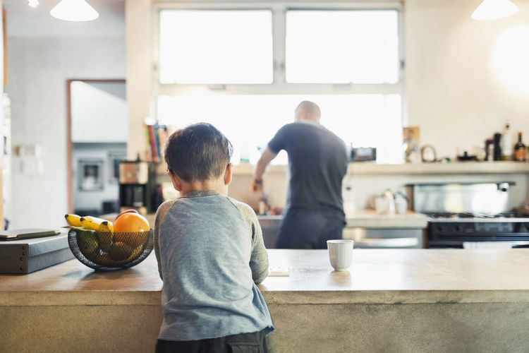 Rear view of father and son in kitchen