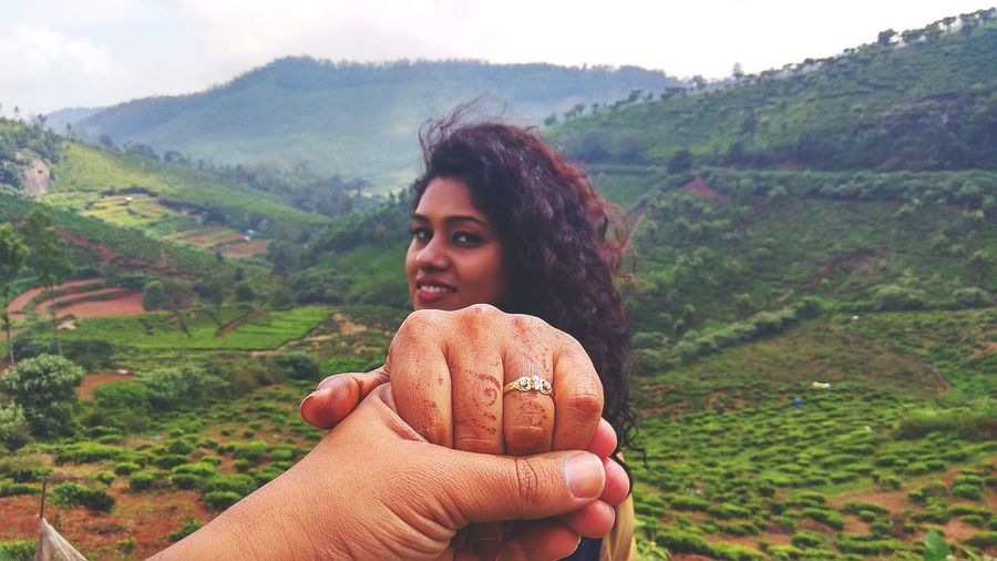 Portrait of beautiful young woman holding hands on land