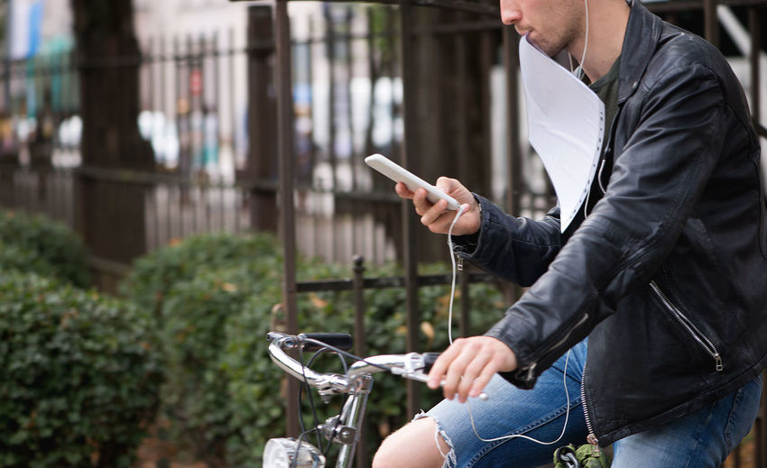 Midsection of man using mobile phone while riding bicycle