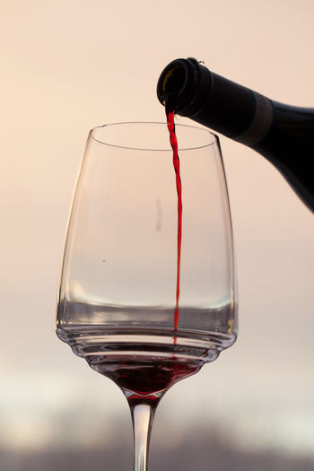 Cropped image of bottle pouring red wine in glass