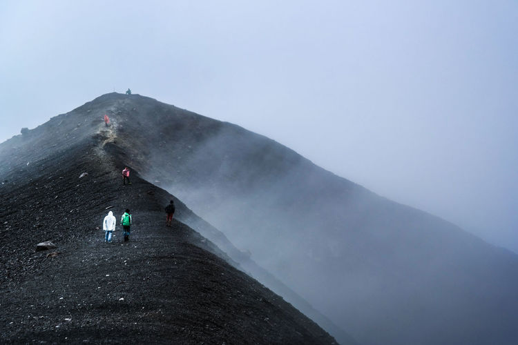 People walking on mountain during foggy weather