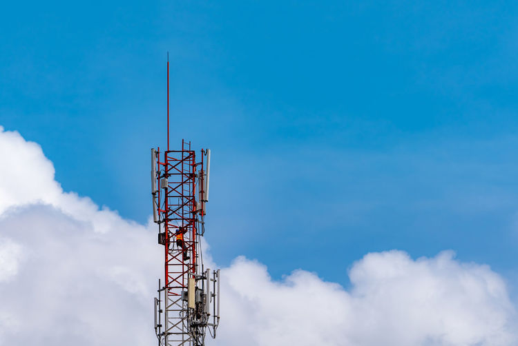 Telecommunication tower with blue sky and white clouds. worker installed 5g equipment.
