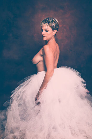 Semi-naked woman wearing tulle tutu against black background