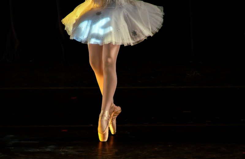 Ballerina from the waist down toe dancing against a black background