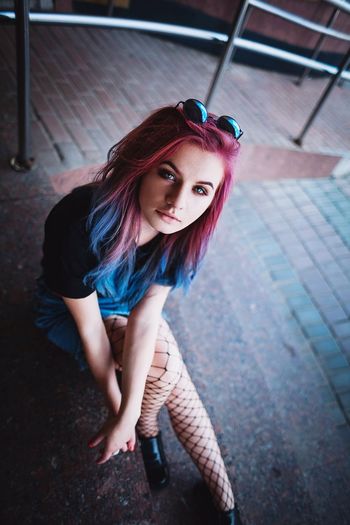 Beautiful young hipster sitting on steps at city
