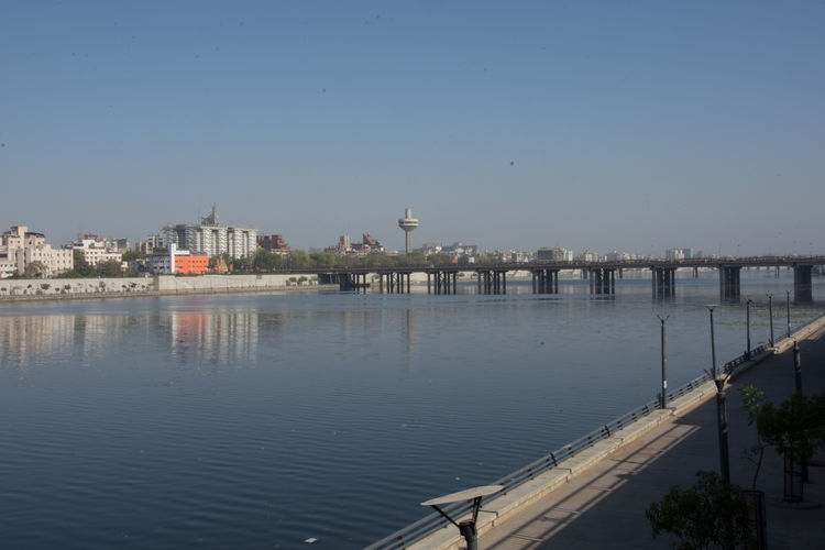 Scenic view of river by buildings against clear blue sky