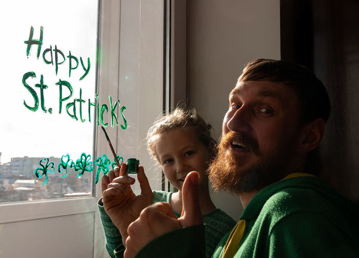 Drawing st. patrick's day father daughter painting green three-leaved shamrocks.stay home new normal