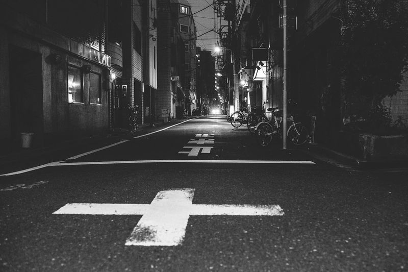 Arrow symbol on road amidst buildings in city