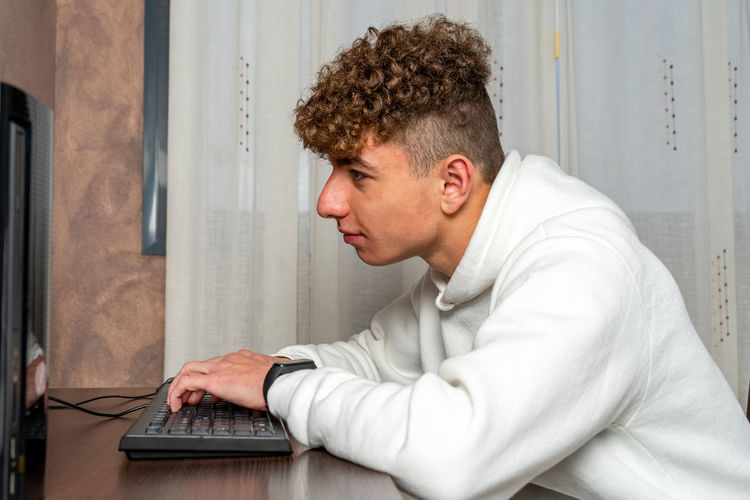 Side view of man using laptop at home