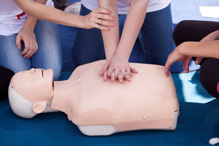 Midsection of paramedics performing cpr on mannequin