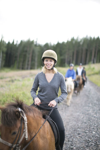 Smiling mid adult woman riding on horse