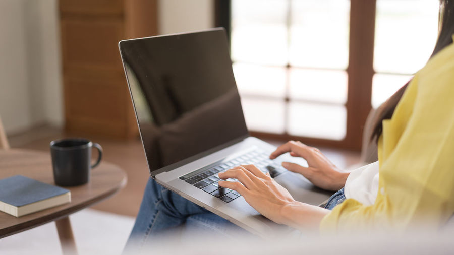 Midsection of woman using laptop on table