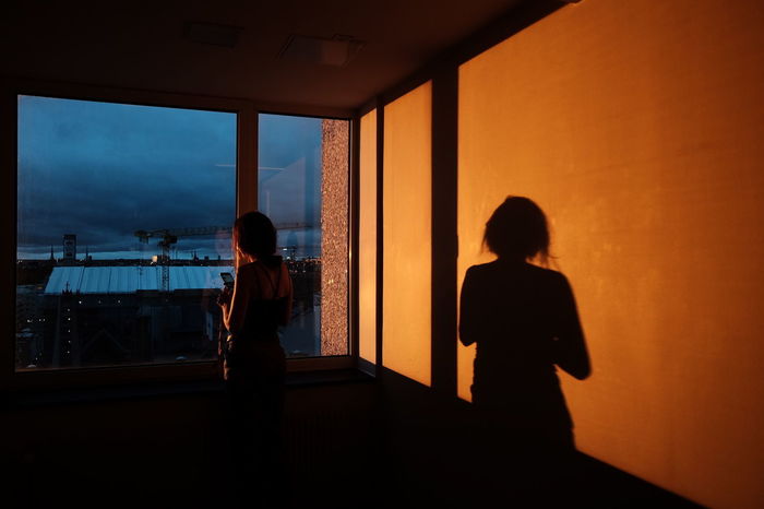 SILHOUETTE OF WOMAN LOOKING THROUGH WINDOW