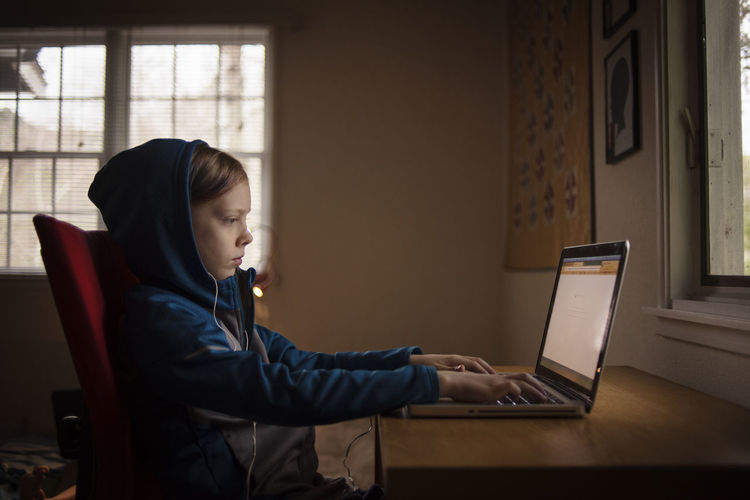 Side view of boy using laptop while sitting at home